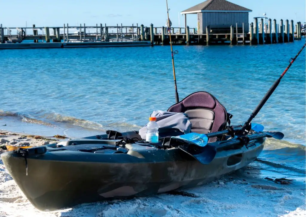 A kayak resting on the beach with an example solution to the question: How do I adjust and make my kayak seat higher?