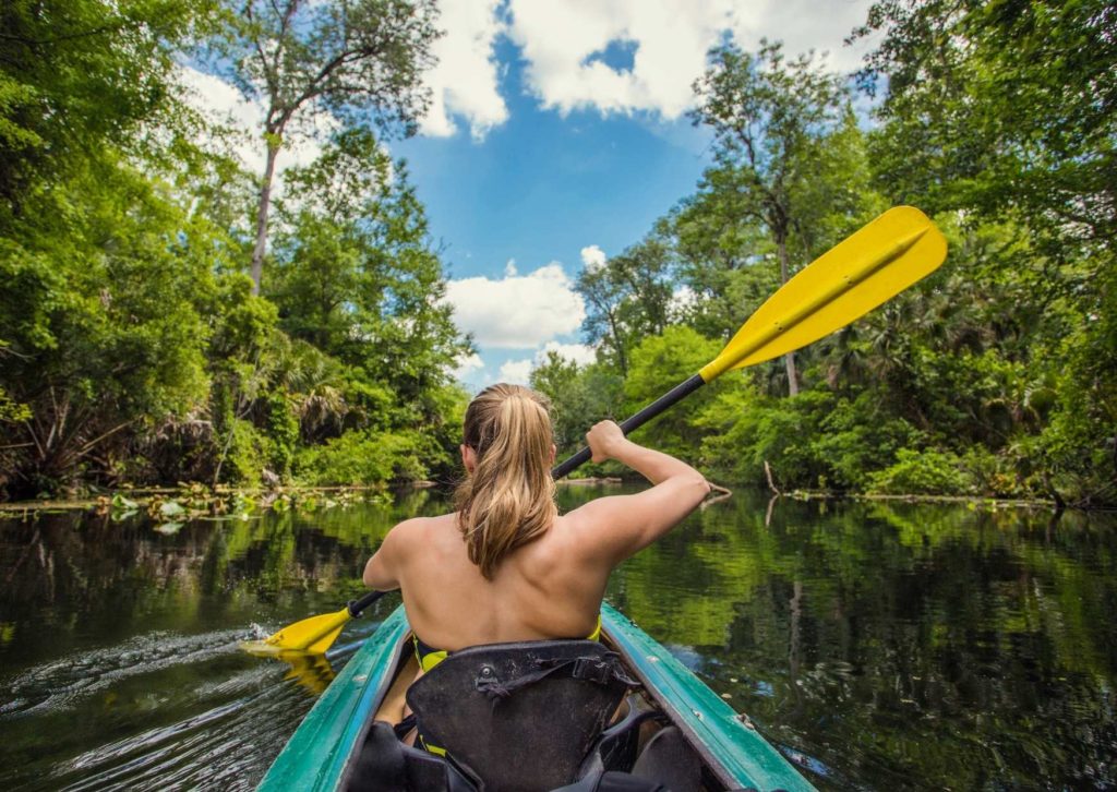 A woman paddling and enjoying the benefits of kayaking.