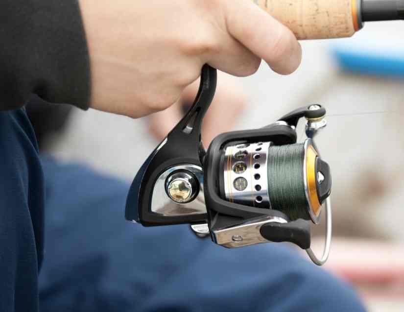 A man using a fishing reel, wondering is a 2500 reel good for surf fishing?