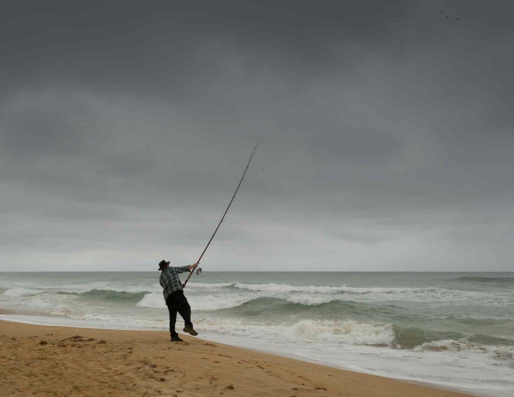 A man beach fishing wondering What is the difference between a surf casting rod and a surf spinning rod