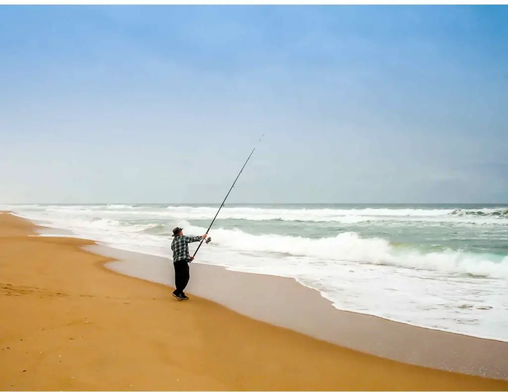A man casting a rod thinking Can you surf cast with a spinning rod?